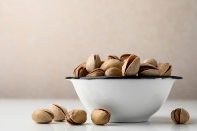 Bowl and pistachio nuts on white table