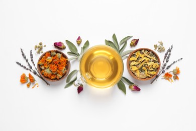 Photo of Freshly brewed tea and dried herbs on white background, top view