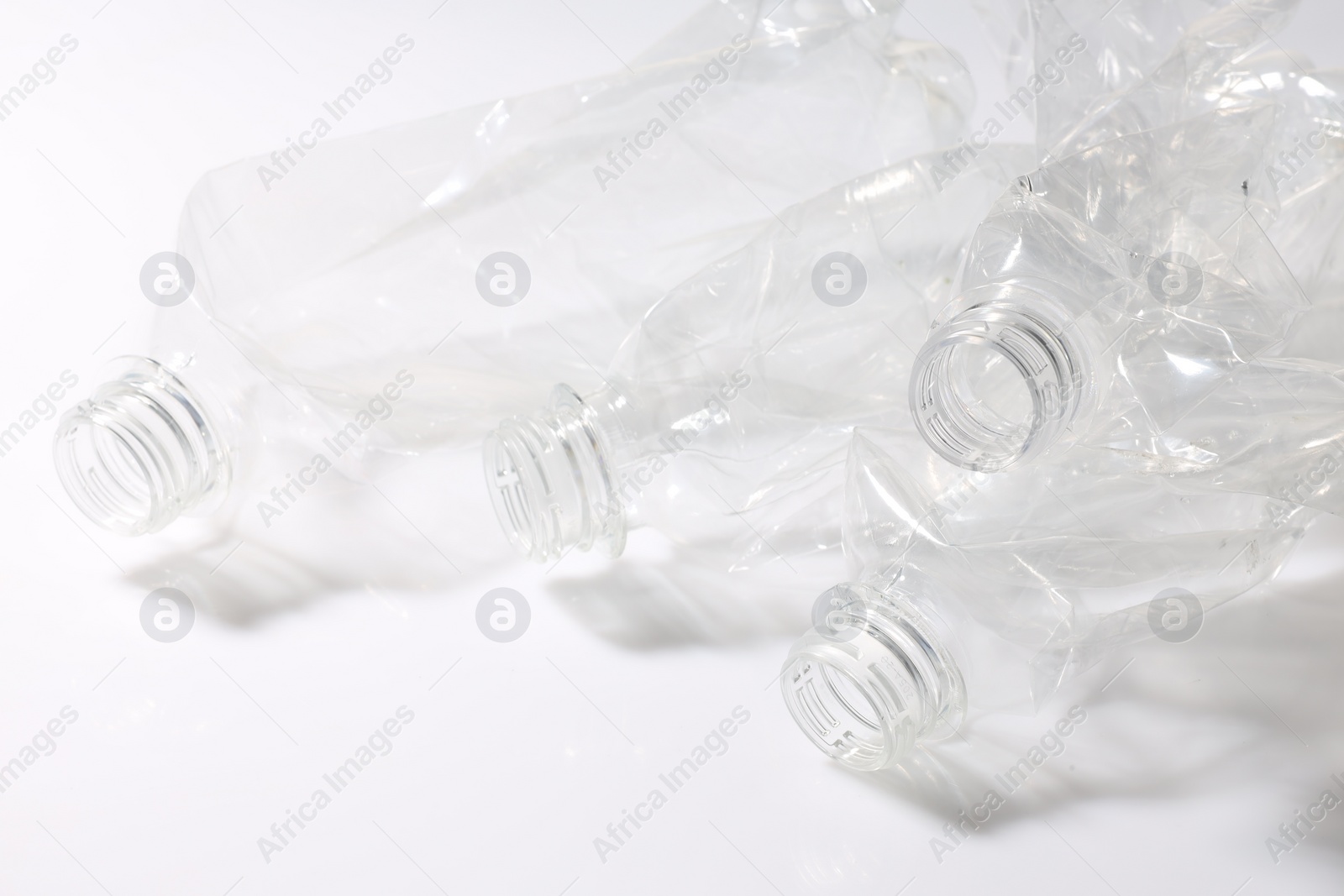 Photo of Crumpled disposable plastic bottles on white background