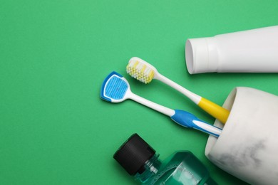 Photo of Flat lay composition with tongue cleaner and teeth care products on green background, space for text