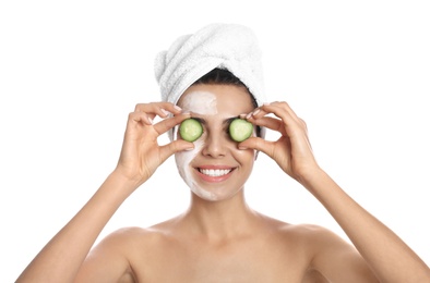 Photo of Happy young woman with organic mask on her face holding cucumber slices against white background