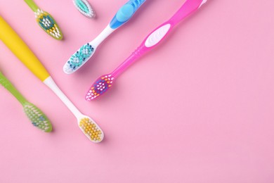 Photo of Many different toothbrushes on pink background, flat lay. Space for text