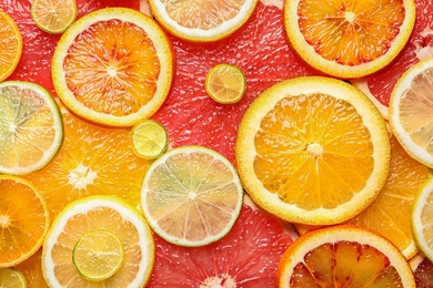 Slices of fresh citrus fruits as background, top view