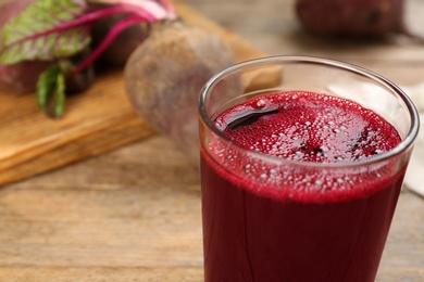 Photo of Freshly made beet juice in glass on wooden table, closeup