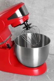 Photo of Modern red stand mixer on light gray marble table, closeup