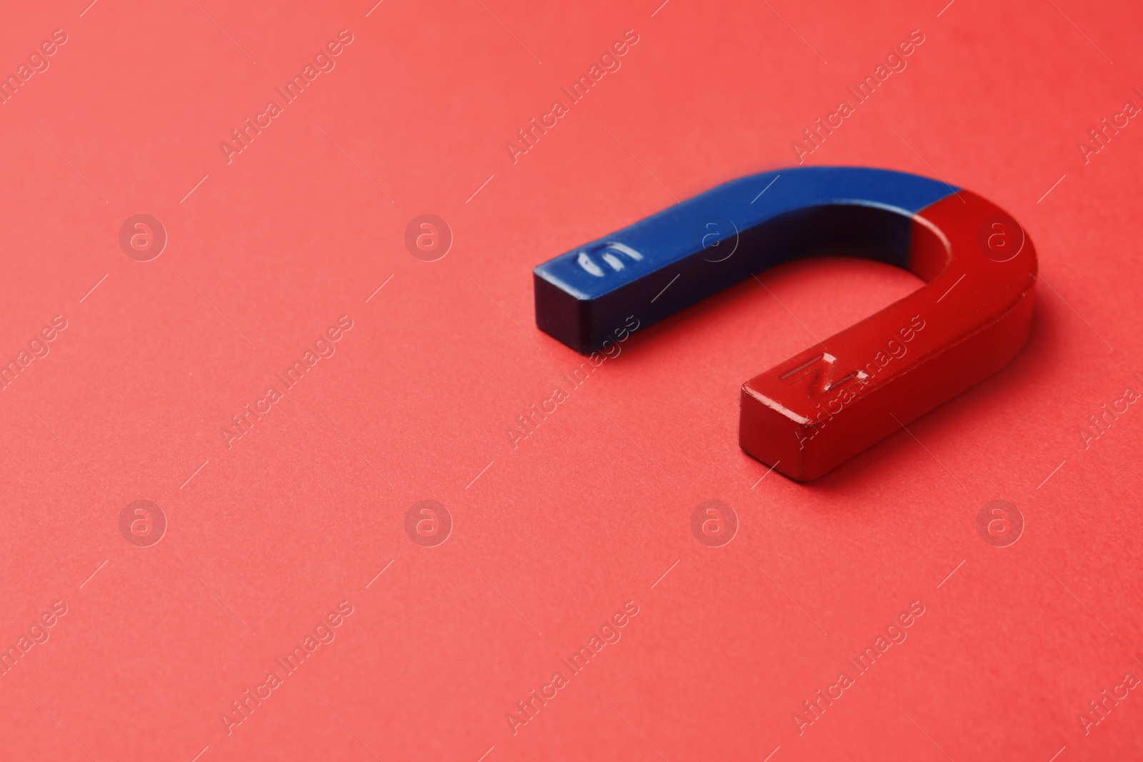 Photo of Red and blue horseshoe magnet on color background. Space for text