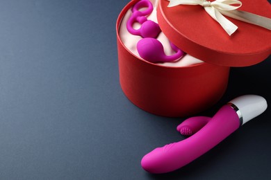 Photo of Pink sex toys and gift box on dark blue background, space for text