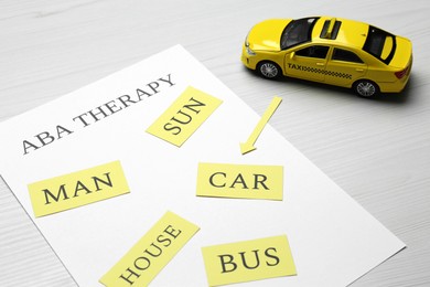Photo of Taxi car model and paper sheet with phrase ABA Therapy on white wooden table