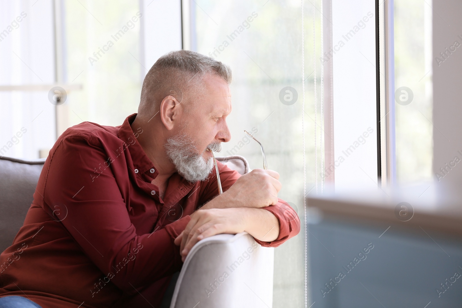 Photo of Depressed senior man sitting in armchair indoors