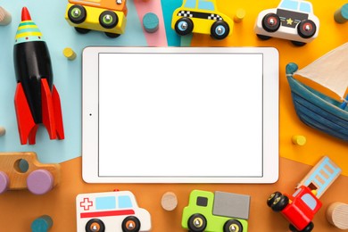 Photo of Modern tablet and toys on color background, flat lay. Space for text