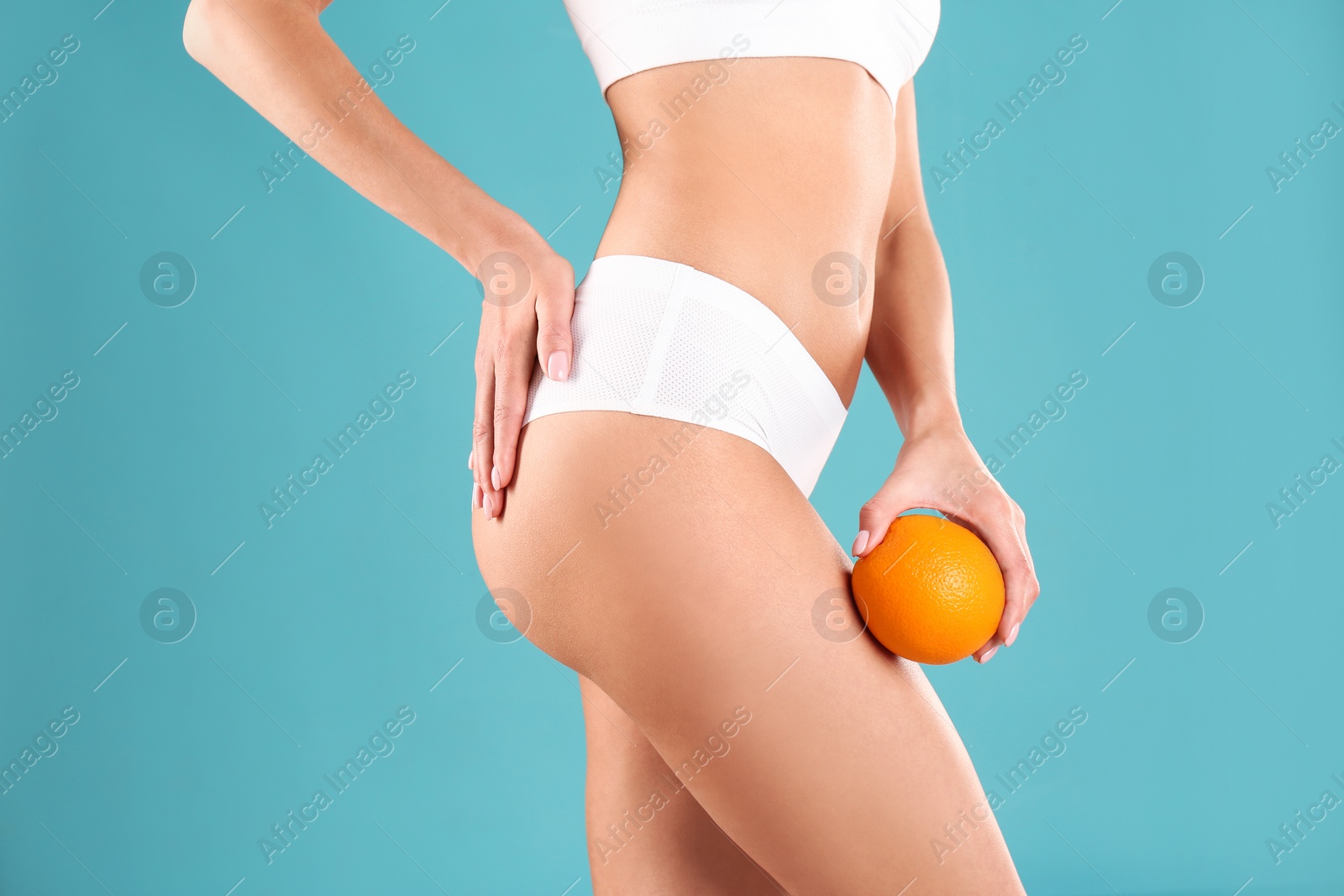 Photo of Closeup view of slim woman in underwear with orange on color background. Cellulite problem concept