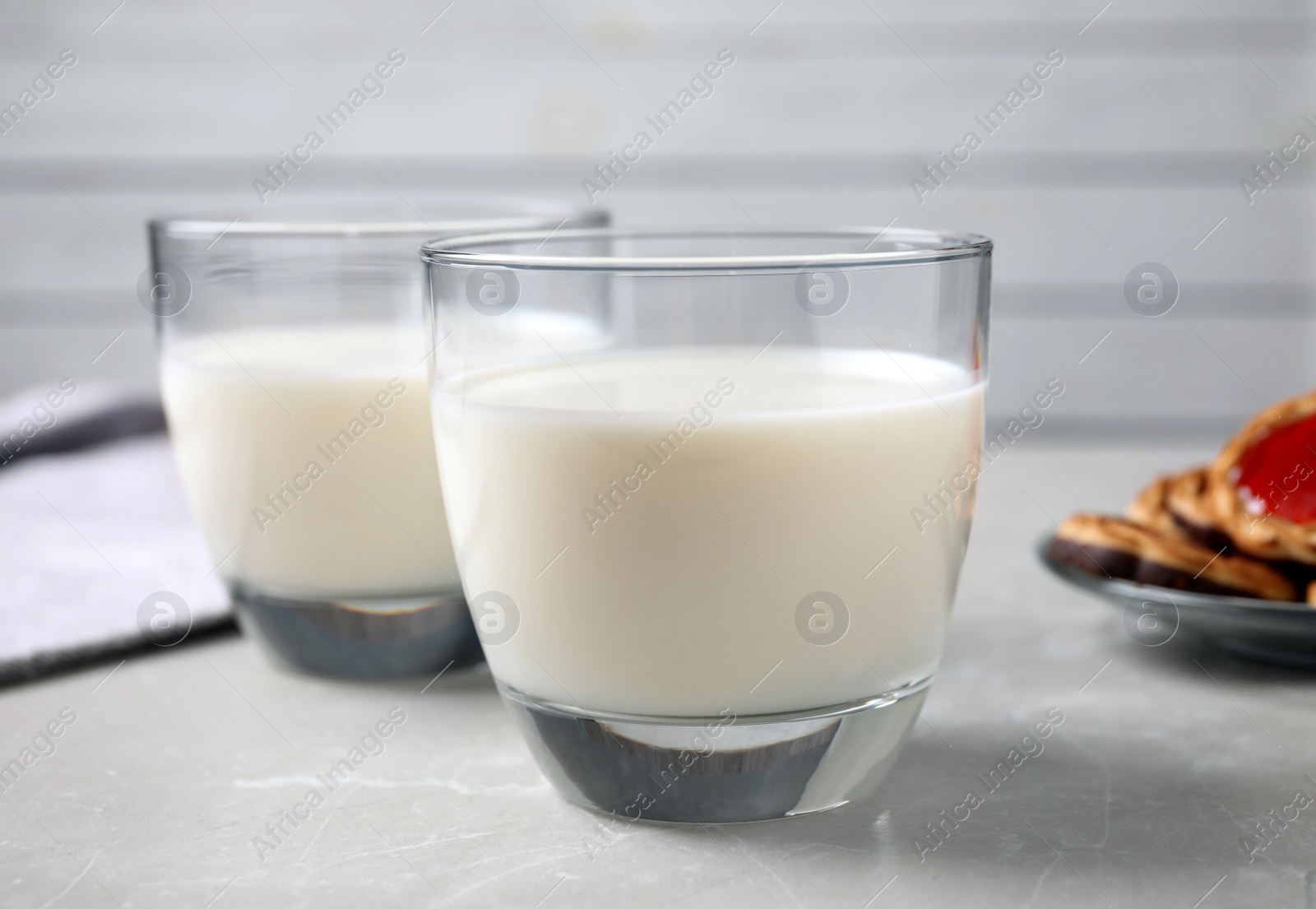 Photo of Glasses of delicious milk on light table