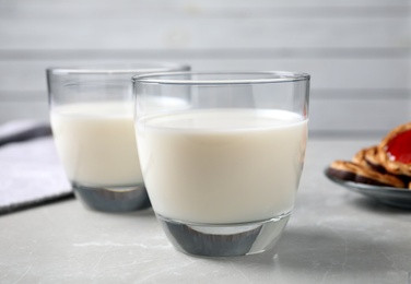 Photo of Glasses of delicious milk on light table