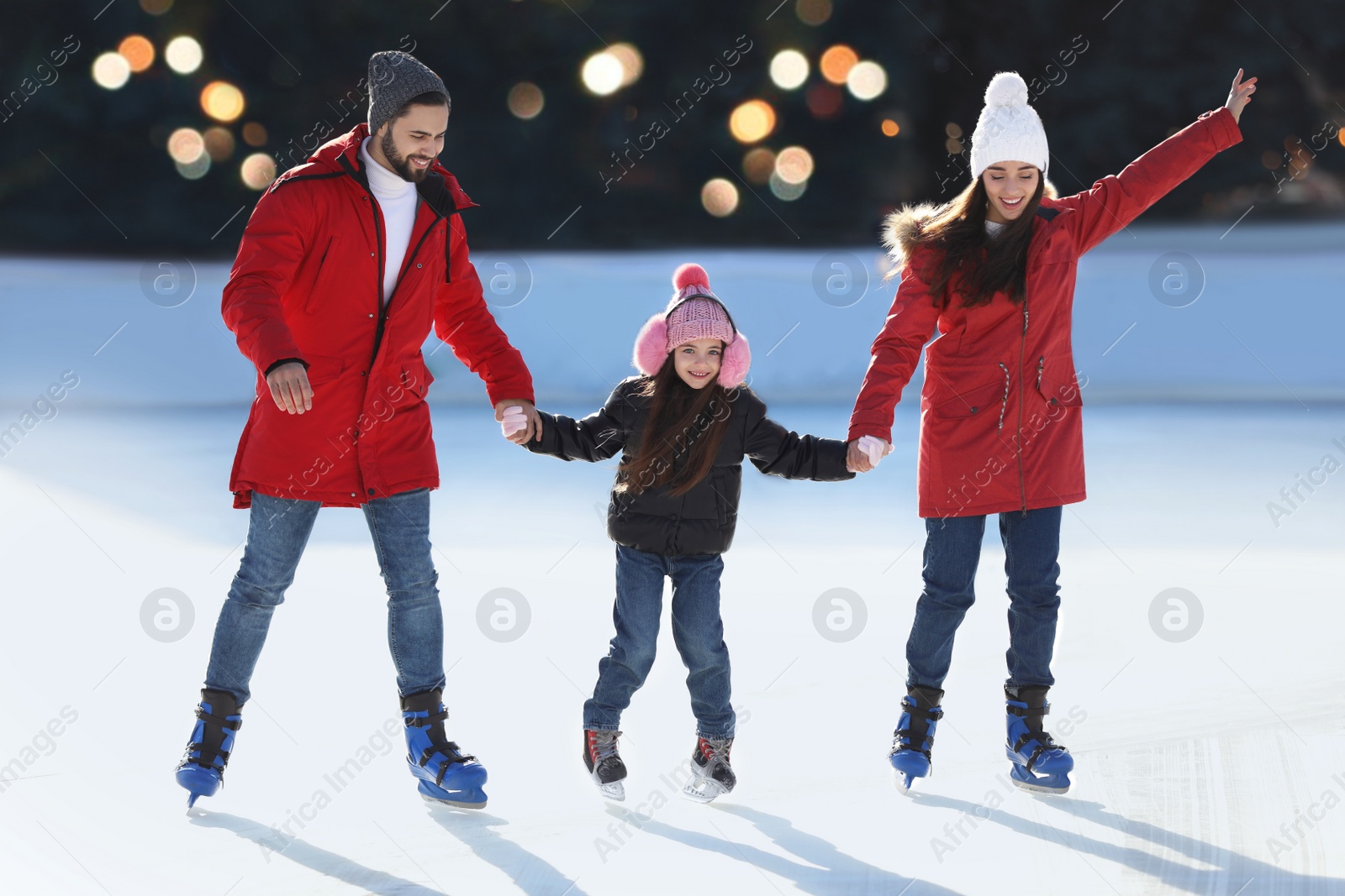 Image of Happy family spending time together at outdoor ice skating rink