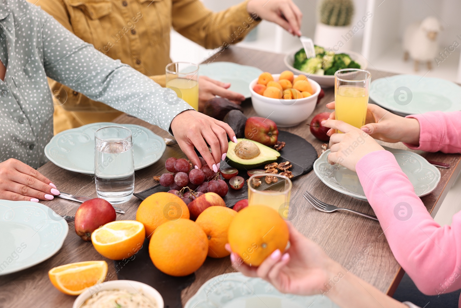 Photo of Friends eating vegetarian food at wooden table indoors, closeup