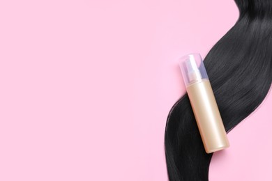Photo of Spray bottle with thermal protection and lockblack hair on pink background, flat lay. Space for text
