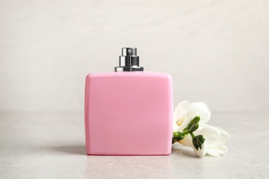 Photo of Bottle of perfume and beautiful freesia flower on light table
