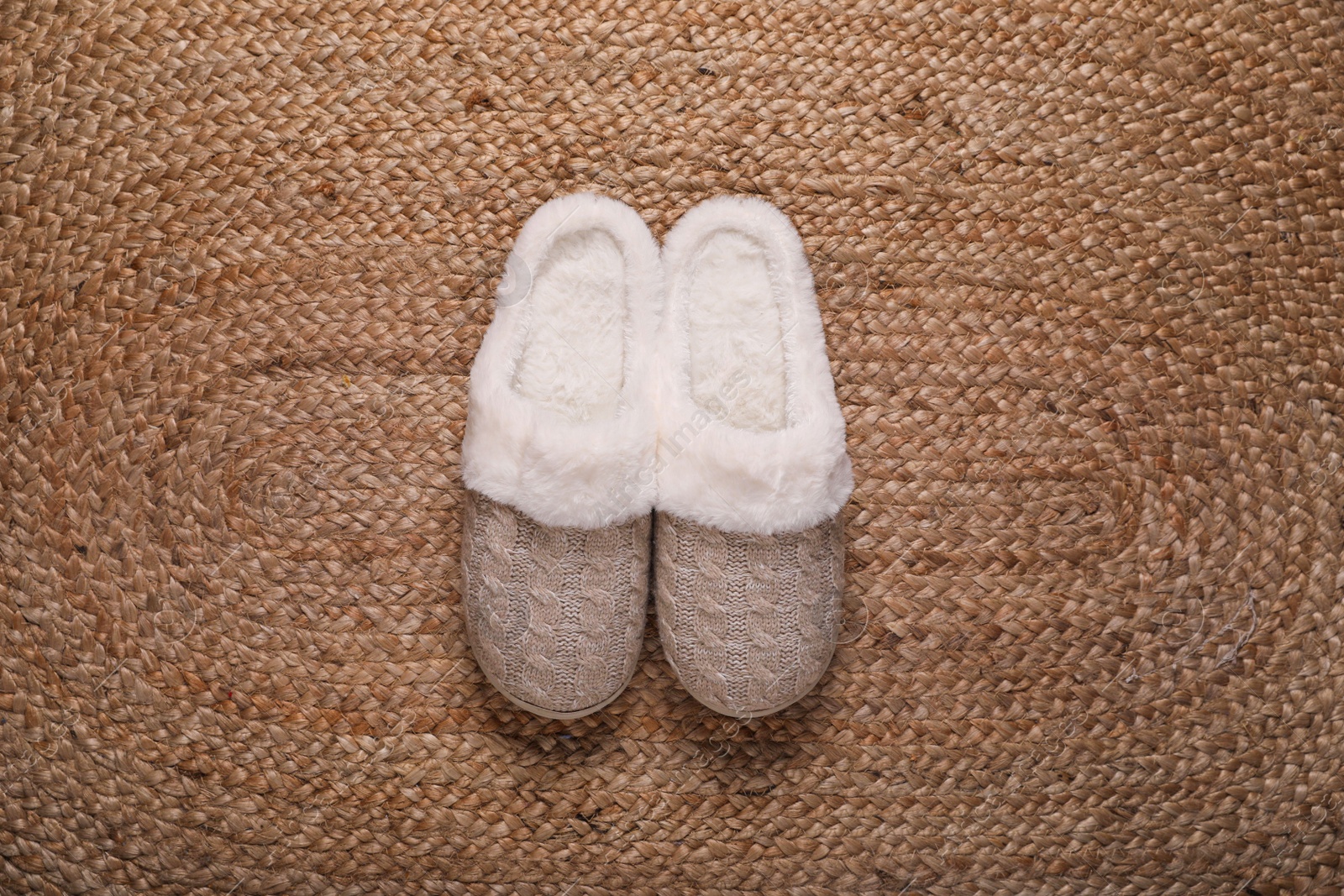 Photo of Pair of beautiful soft slippers on wicker carpet, top view