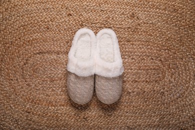 Photo of Pair of beautiful soft slippers on wicker carpet, top view