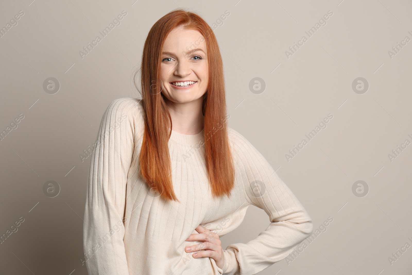 Photo of Candid portrait of happy young woman with charming smile and gorgeous red hair on beige background