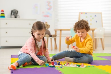 Cute little children playing with math game Fishing for Numbers on puzzle mat in kindergarten