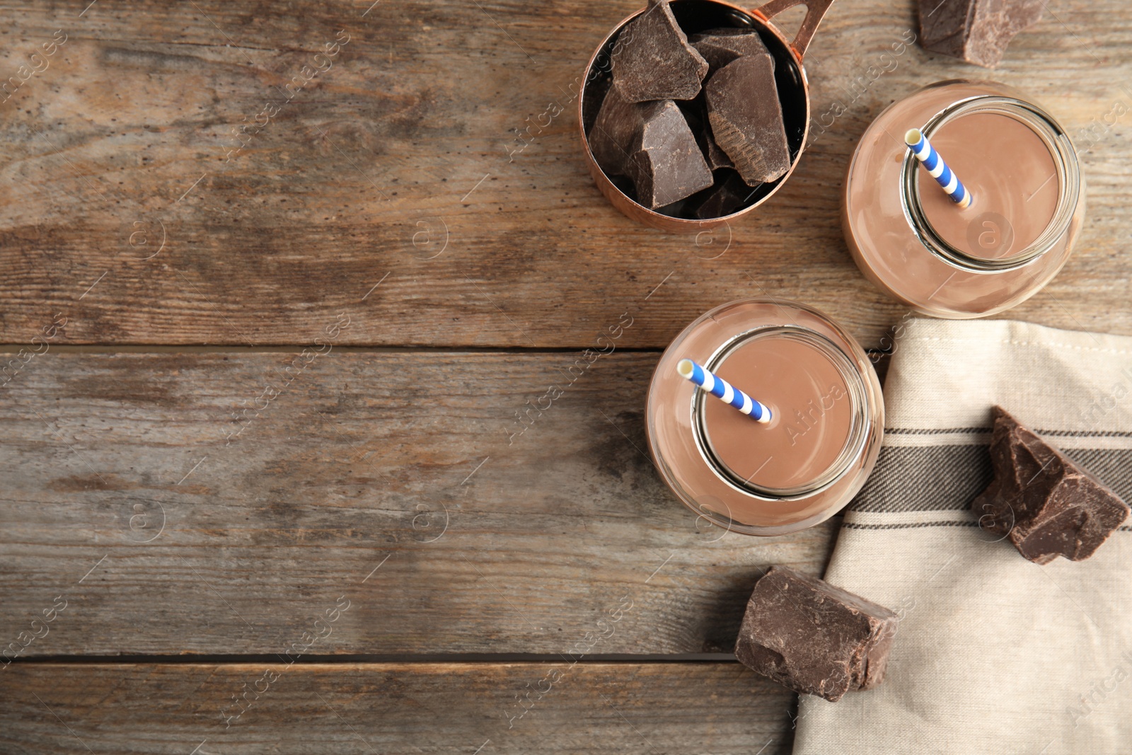 Photo of Flat lay composition with jars of tasty chocolate milk and space for text on wooden background. Dairy drink