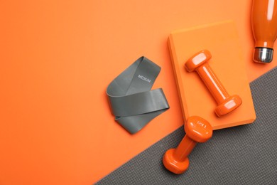 Photo of Dumbbells, yoga block, mat, thermo bottle and fitness elastic band on orange background, flat lay. Space for text