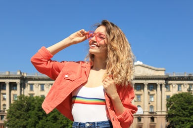 Photo of Portrait of happy young woman with heart shaped glasses in city on sunny day