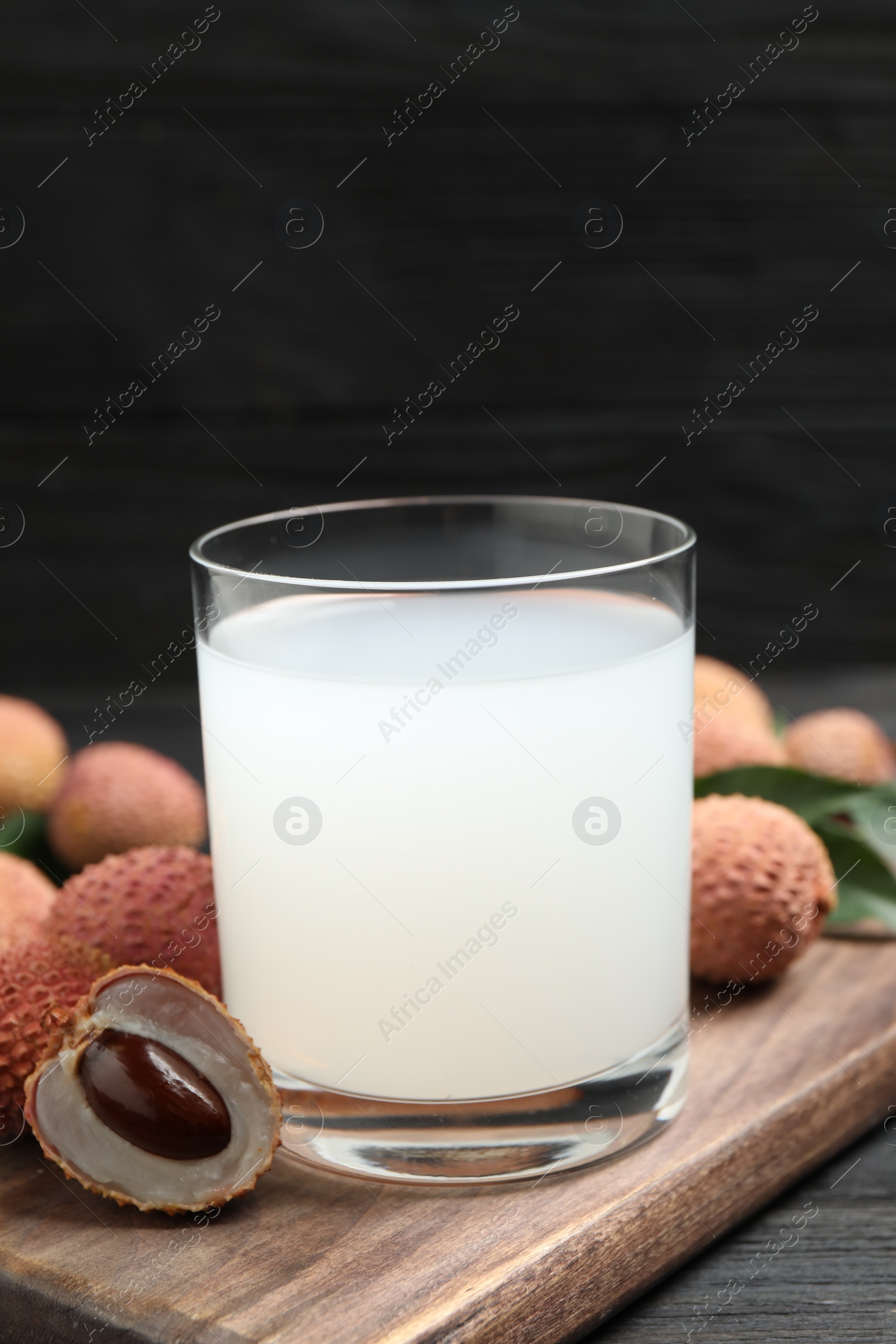 Photo of Lychee juice and fresh fruits on black wooden table