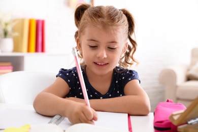 Cute little girl doing homework at table