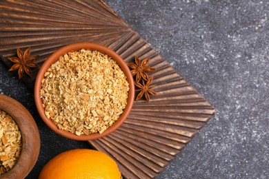 Photo of Bowl of dried orange zest seasoning, fresh fruit and anise on grey table, flat lay. Space for text