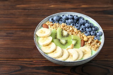 Photo of Tasty smoothie bowl with fresh fruits and oatmeal on wooden table, space for text