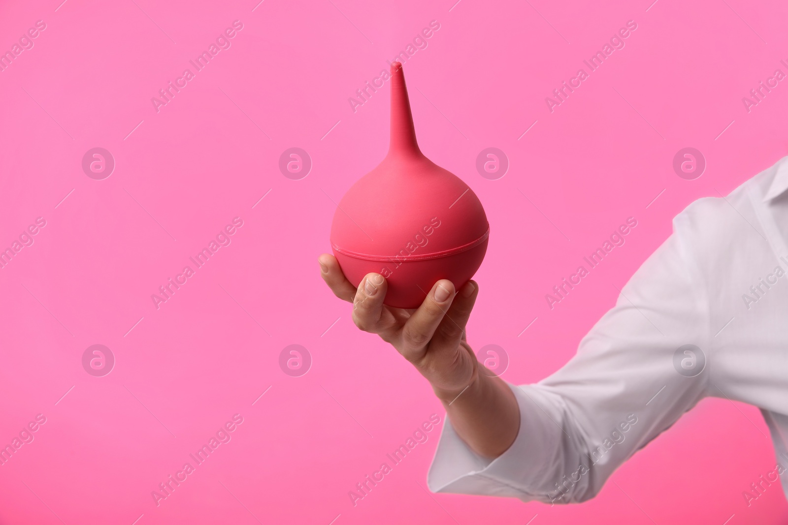 Photo of Woman holding enema on pink background, closeup