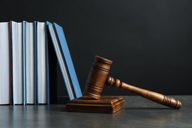 Wooden gavel and books on table against dark background. Law concept