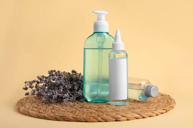 Photo of Bottles with cosmetic products and dried lavender flowers on beige background