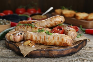 Tasty fresh grilled sausages with vegetables on wooden table, closeup