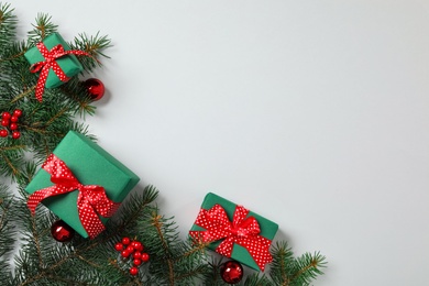 Gift boxes, Christmas balls and fir branches on grey background, flat lay. Space for text