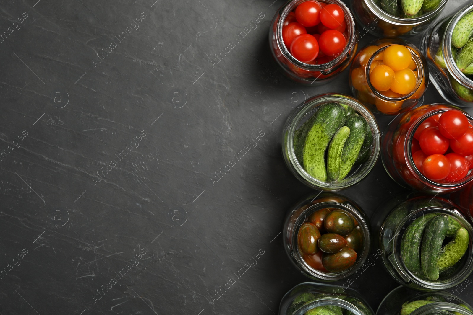 Photo of Pickling jars with fresh vegetables on black table, flat lay. Space for text