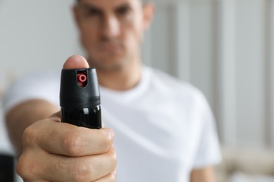 Photo of Man using pepper spray at home, focus on hand