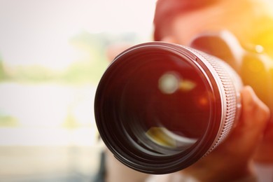 Photographer with professional camera on blurred background, closeup