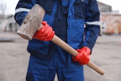 Man in uniform with sledgehammer outdoors, closeup