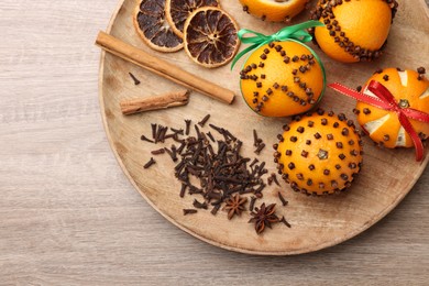 Photo of Pomander balls made of tangerines with cloves on wooden table, top view