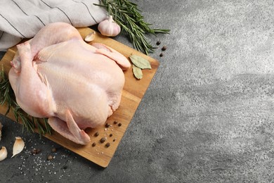 Fresh raw chicken with spices on grey textured table, flat lay. Space for text