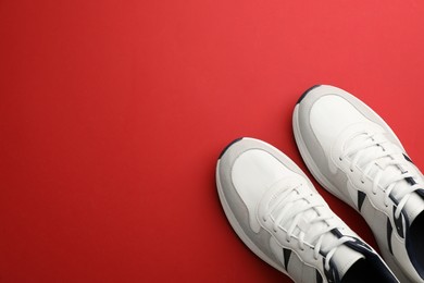 Photo of Pair of stylish sports shoes on red background, flat lay. Space for text