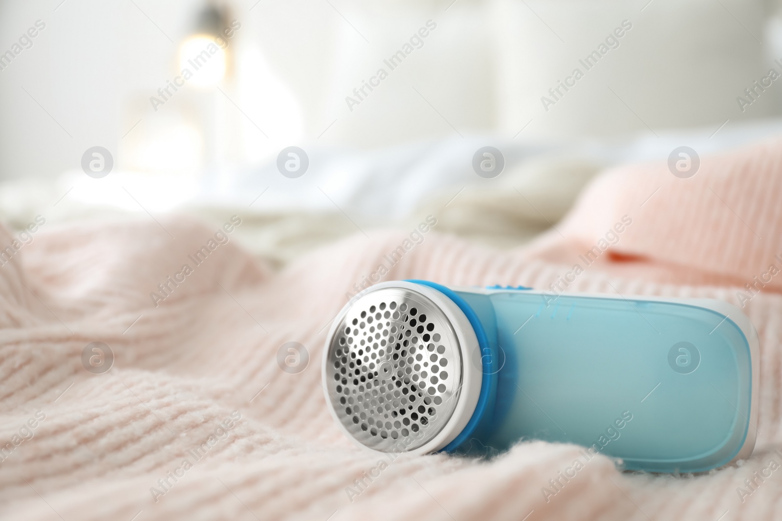 Photo of Modern fabric shaver on pink woolen sweater, closeup. Space for text