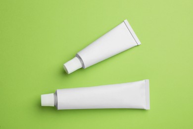 Photo of Blank white tubes of ointment on light green background, flat lay. Space for text