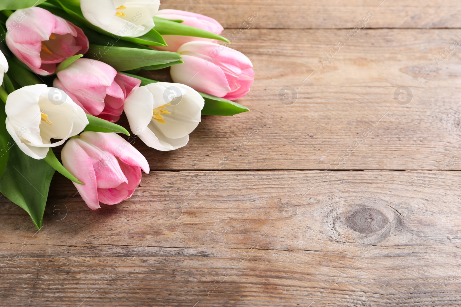 Photo of Beautiful pink spring tulips on wooden background, space for text