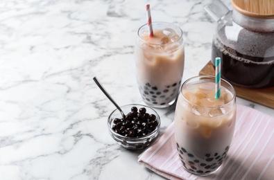 Photo of Bubble milk tea with tapioca balls on white marble table. Space for text