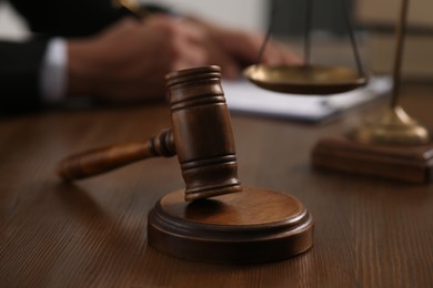 Photo of Law and justice. Closeup of judge working at wooden table, focus on gavel