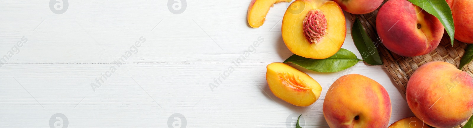 Image of Fresh ripe peaches and green leaves on white wooden table, flat lay. Banner design with space for text